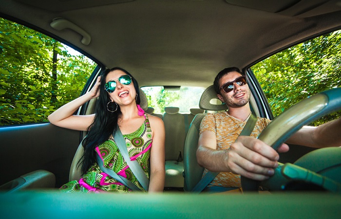 Image of a happy couple driving with sunglasses on.